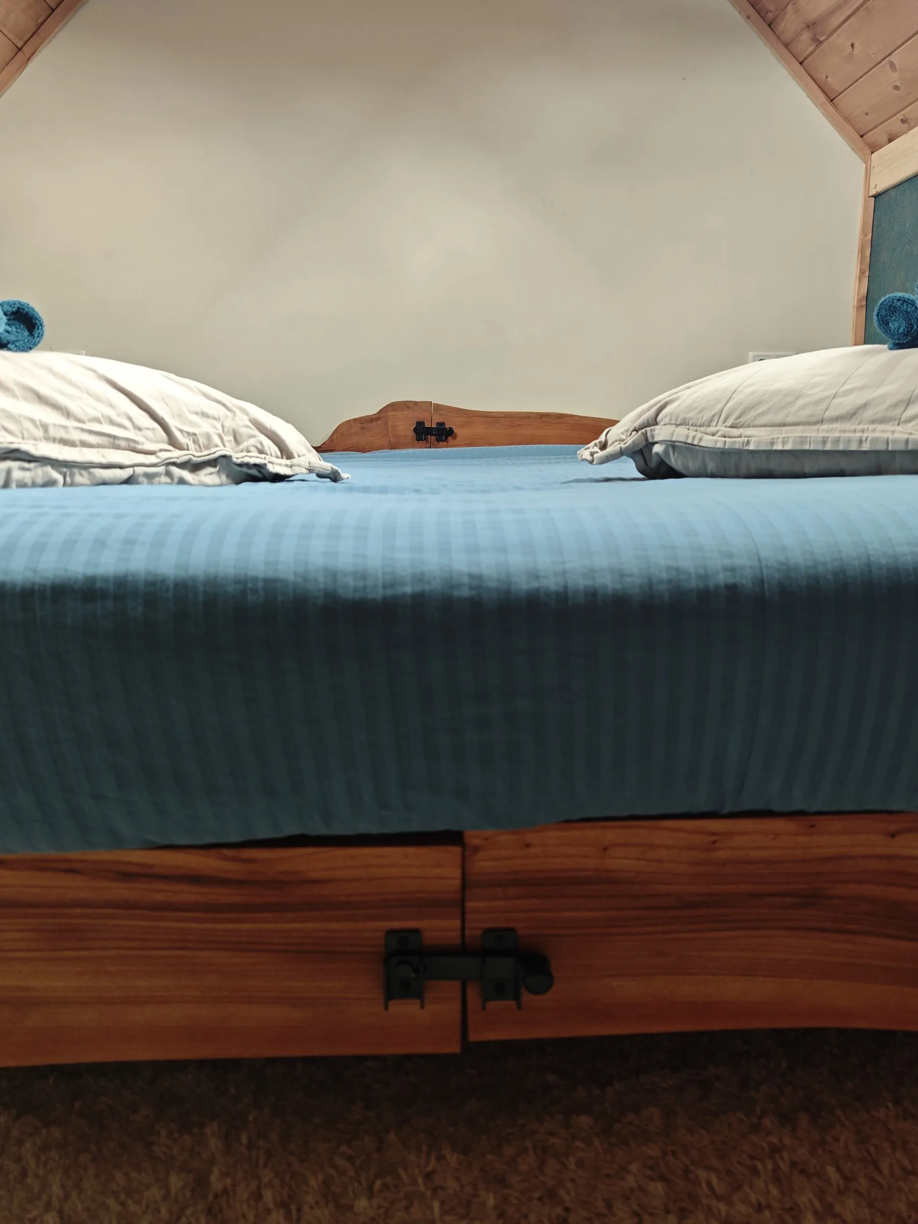 Voeteneind van het bed met een zwarte grendel in het houten frame