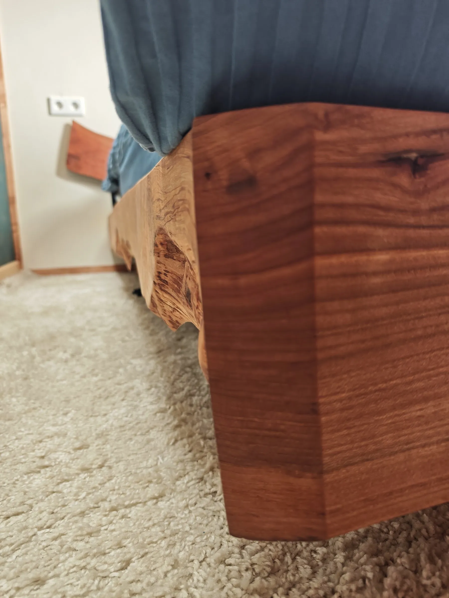 Hoek van een massief houten bedframe met zichtbare nerf