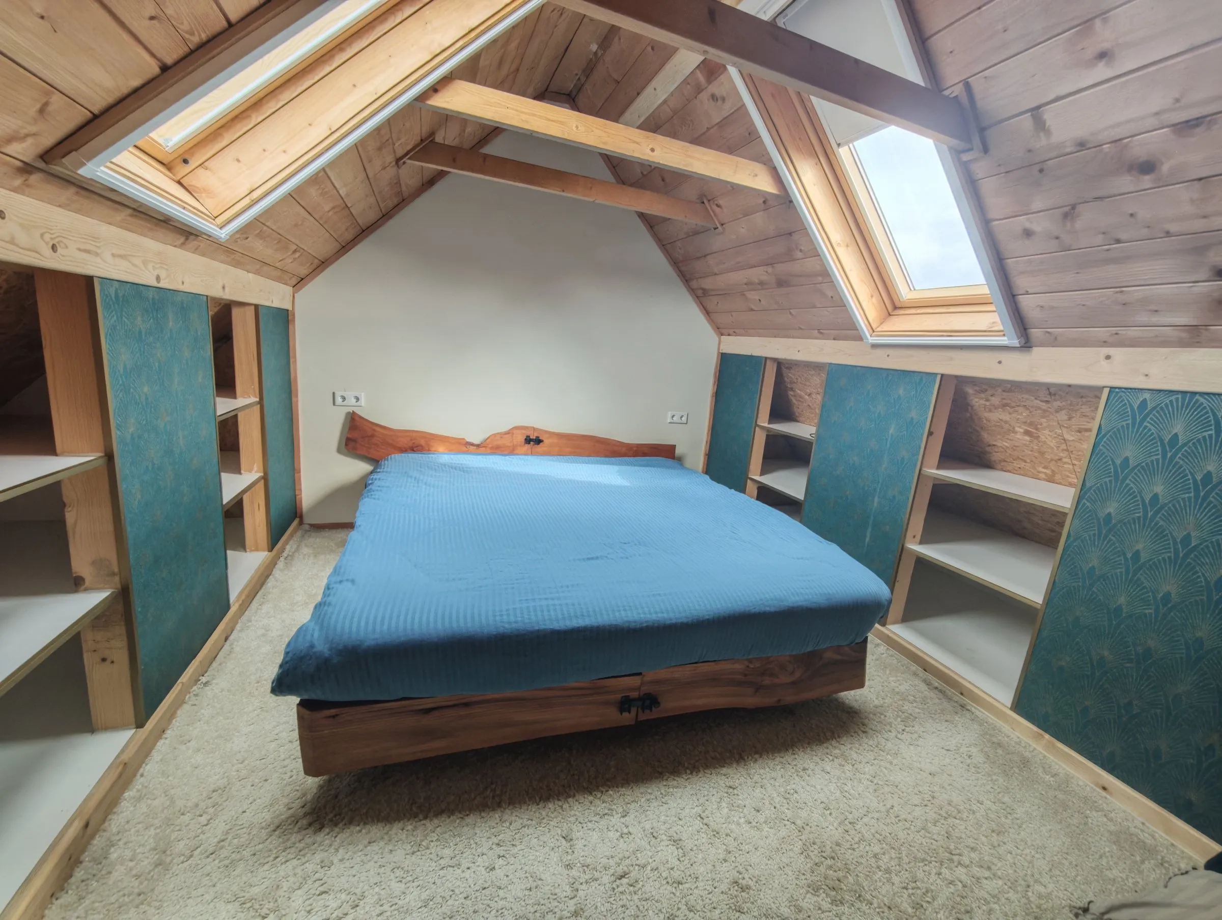 Zolderslaapkamer met bed van massief hout en ingebouwde kasten