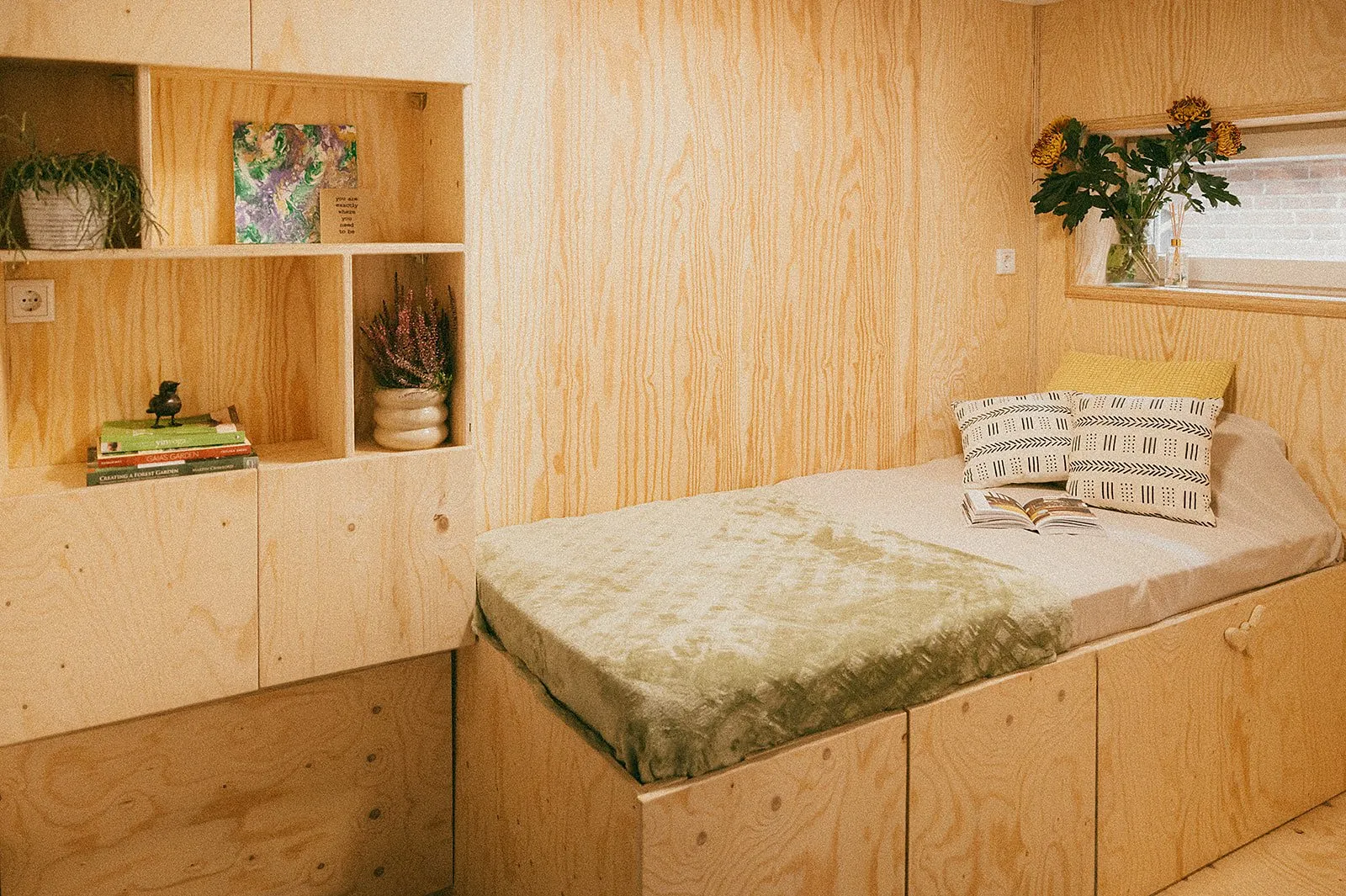 Kamer met wanden, open kasten en een bedbak van multiplex